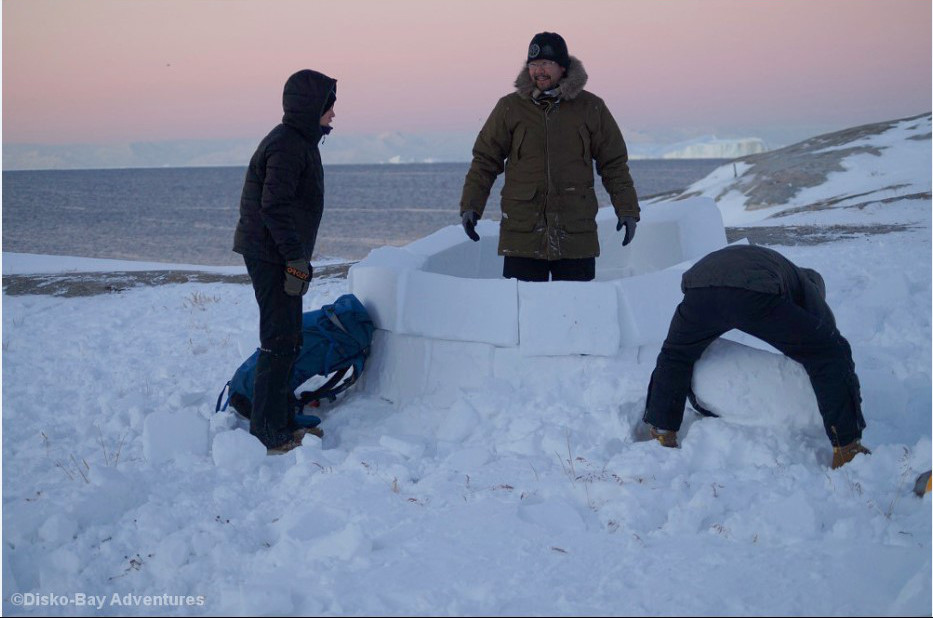 Drei Männer bauen ein Iglu