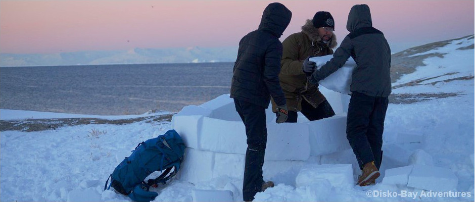 Drei Inuit bauen ein Iglu