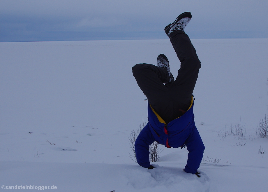 Mann macht Handstand im Schnee