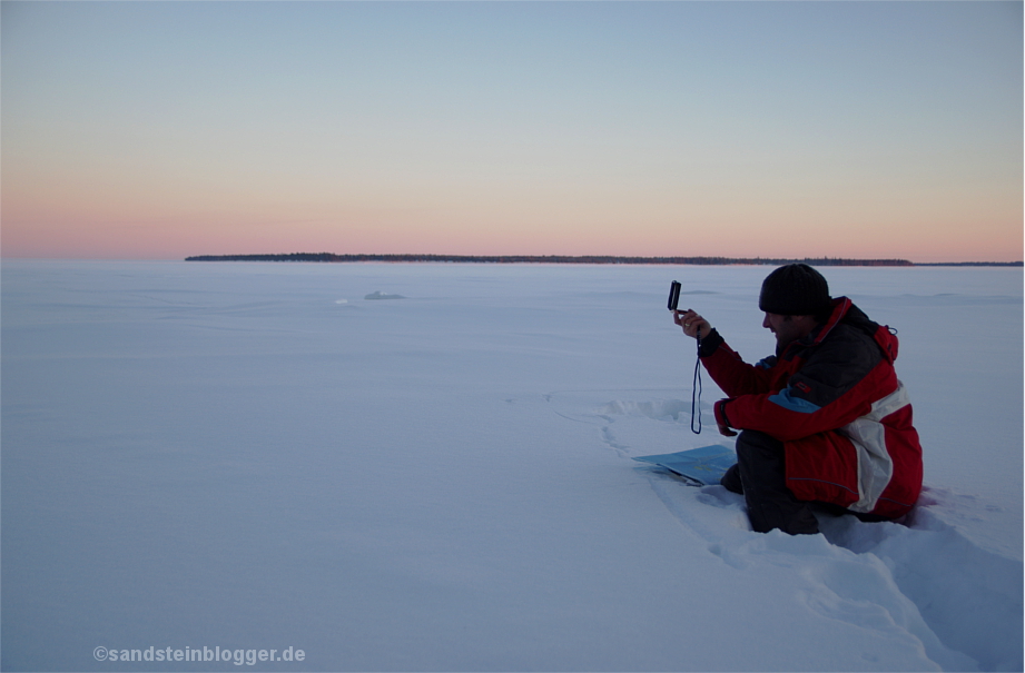 Mann mit Kompass im Schnee beim Anpeilen einer Insel