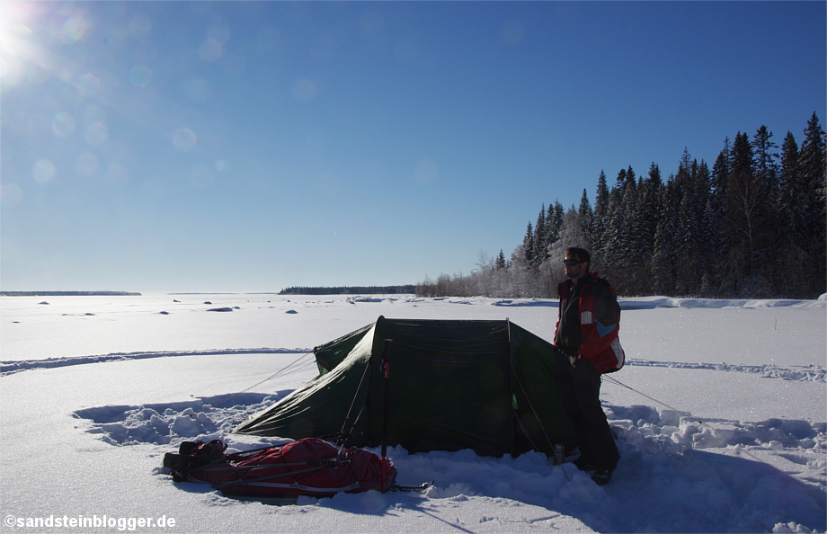 Mann mit Zelt in verschneiter Winterlandschaft