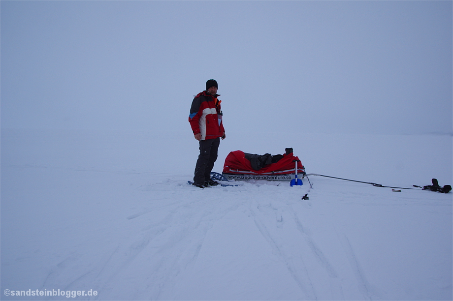 Mann mit Pulka im Schneetreiben