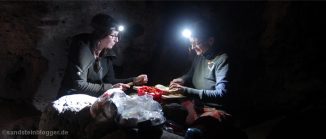 Zwei Frauen mit Stirnlampe schneiden Gemüse, dahinter Felsen