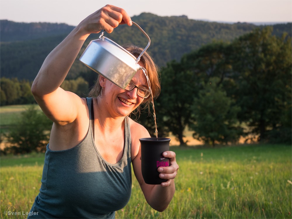 Frau schenkt sich einen Becher Wasser ein.