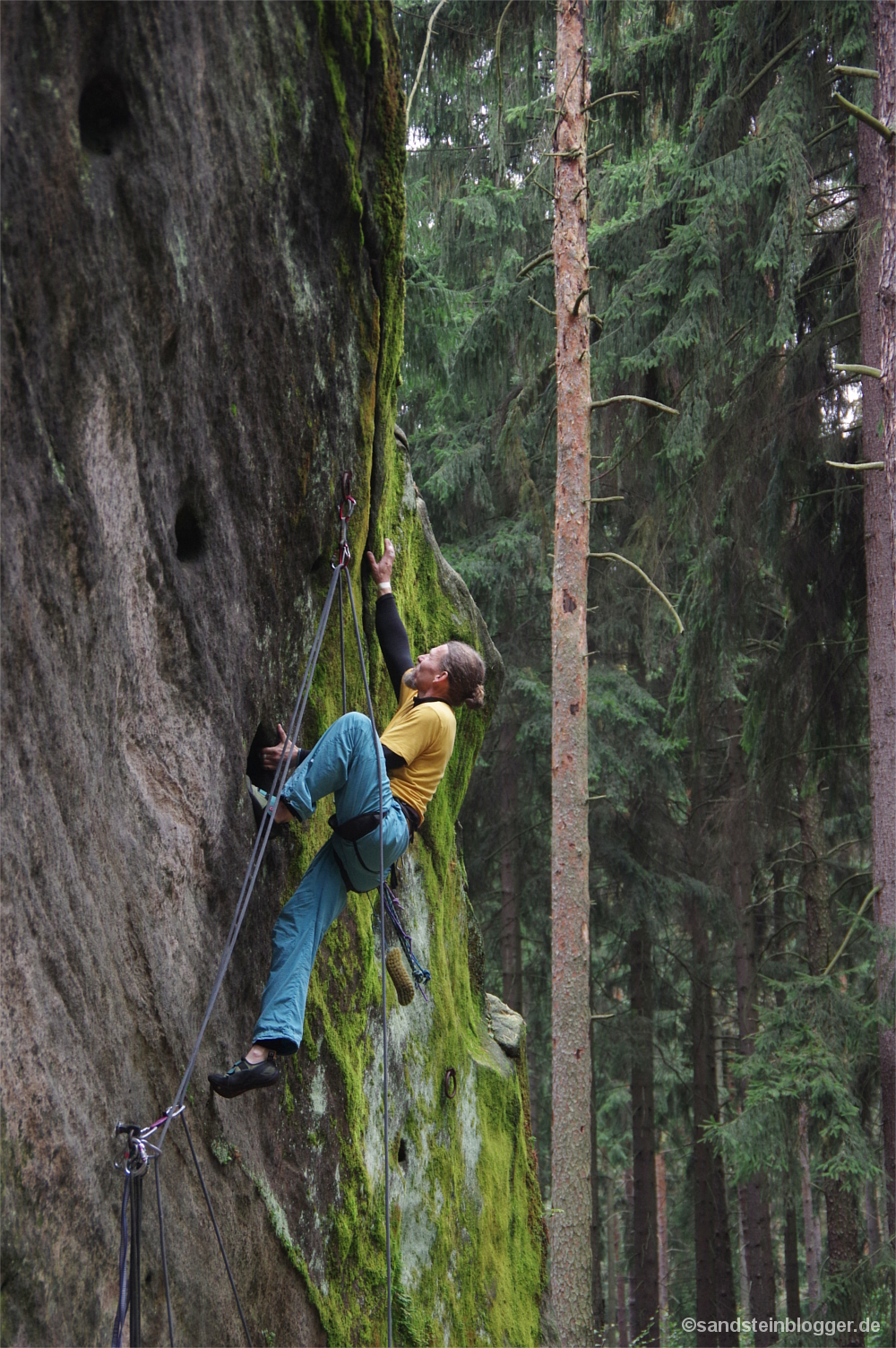 Mann klettert an Felswand