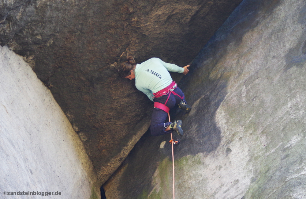 Frau klettert an Felsdach