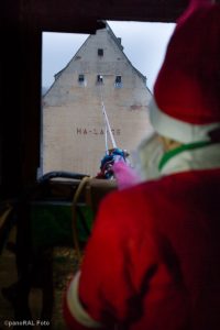 Weihnachtsmann vor Dachfenster, dahinter Hochseil