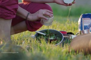 Frau gießt Dressing über einen Topf mit Salat