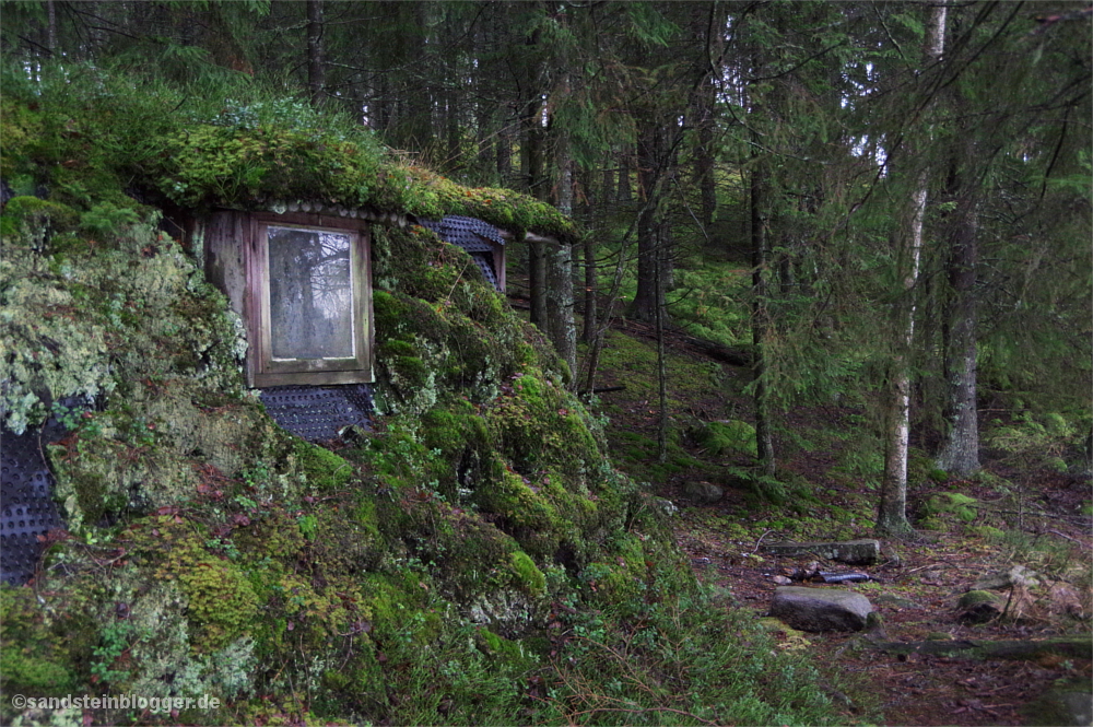 Moosbewachsene Erdhütte im Wald