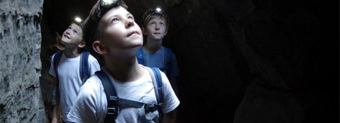 Durch abenteuerliche Felsgassen an der Johanniswacht Drei Jungen mit Stirnlampe in einem Felstunnel