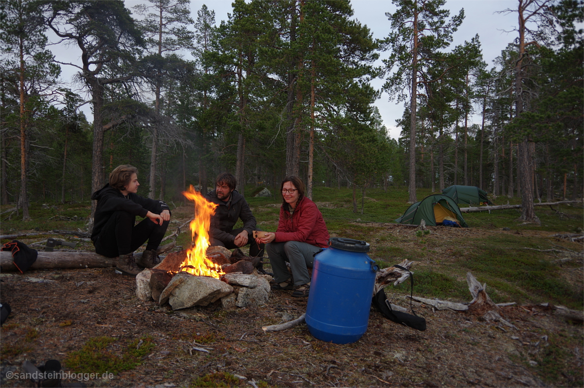 Familie am Lagerfeuer in der finnischen Wildnis