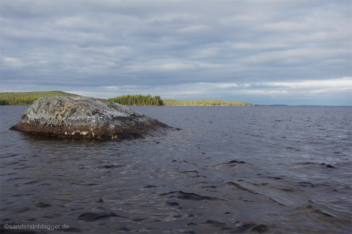 Seenlandschaft im Licht - vorne ein einzelner Felsen im Wasser