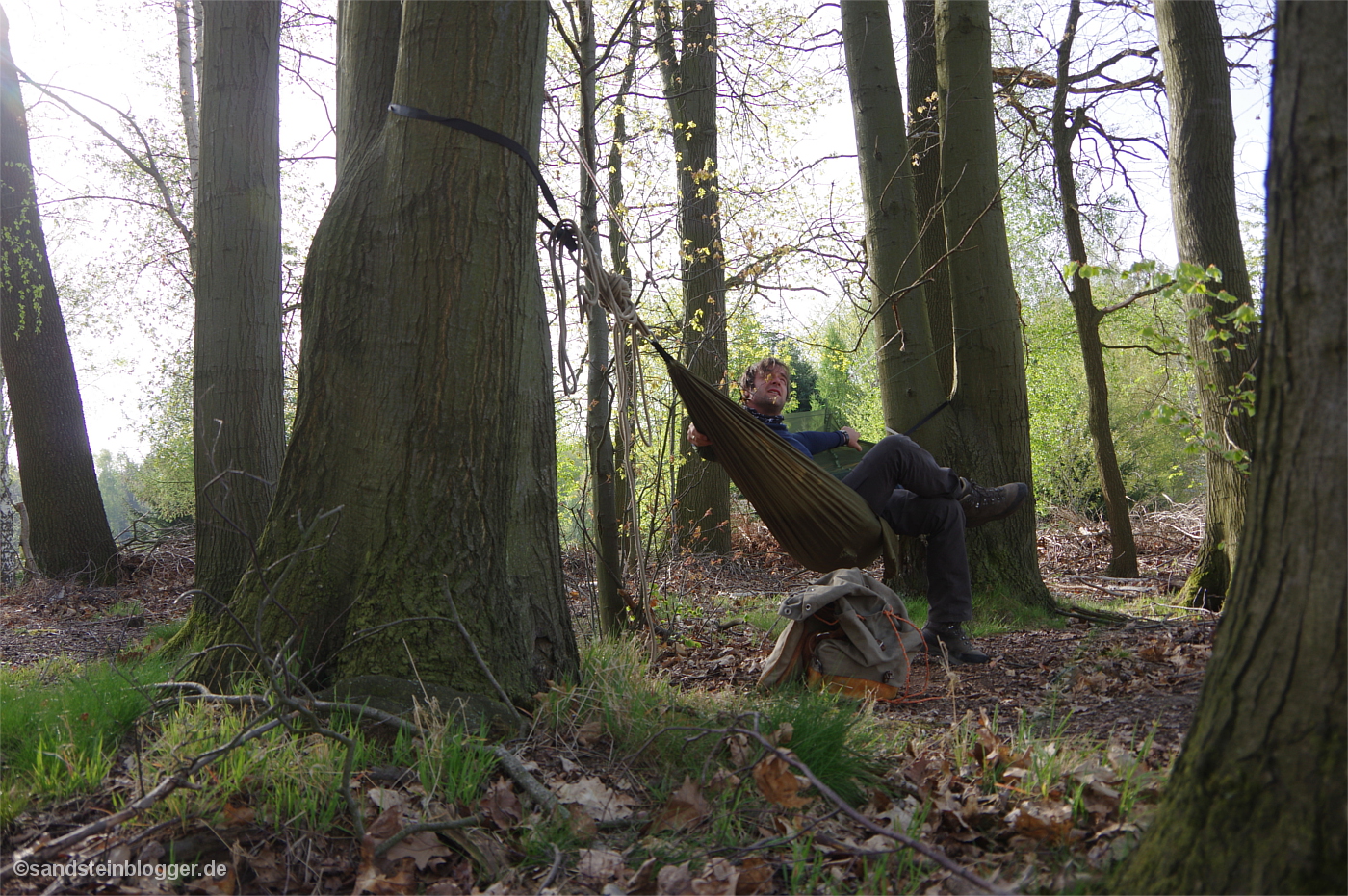 Ein Mann sitzt in einer Hängematte, ringsherum Wald