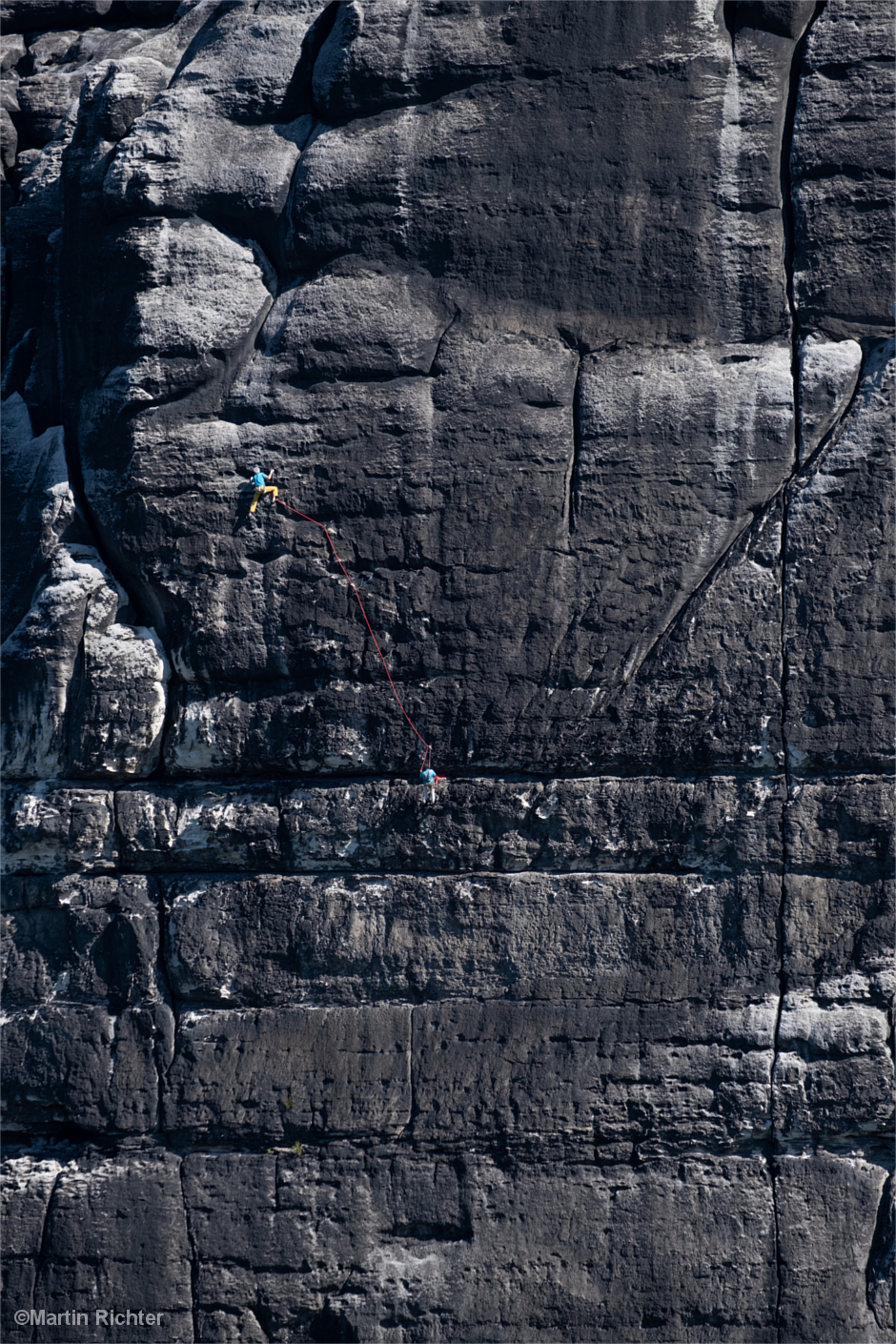 Kletterer an kolossaler Felswand