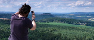 Ein Mann peilt mit einem Kompass einen Tafelberg am Horizont an.