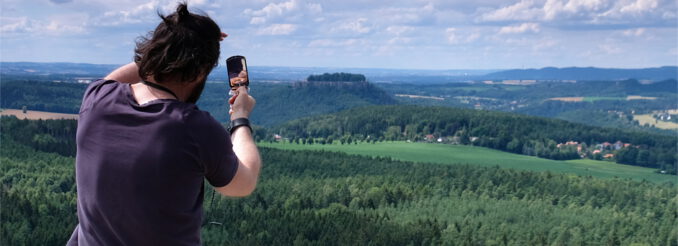 Ein Mann peilt mit einem Kompass einen Tafelberg am Horizont an.